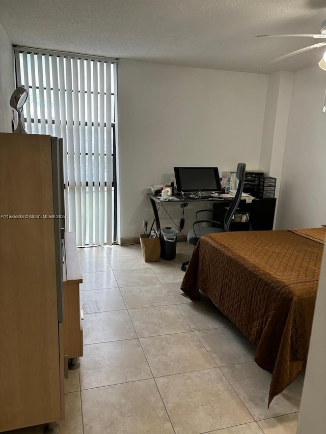 tiled bedroom featuring multiple windows, a textured ceiling, stainless steel refrigerator, and ceiling fan