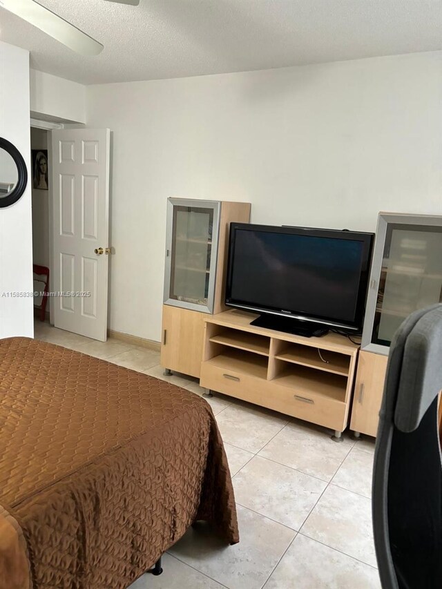 bedroom with ceiling fan, light tile patterned floors, and a textured ceiling