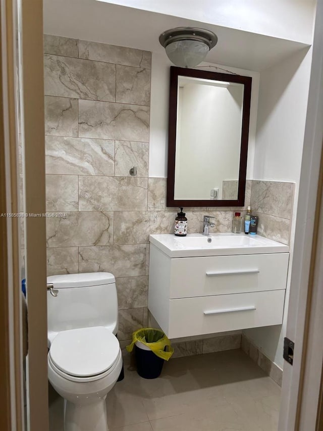 bathroom with tile patterned flooring, vanity, tile walls, and toilet