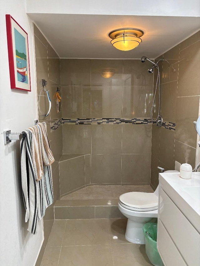 bathroom with tile patterned flooring, a tile shower, vanity, and toilet