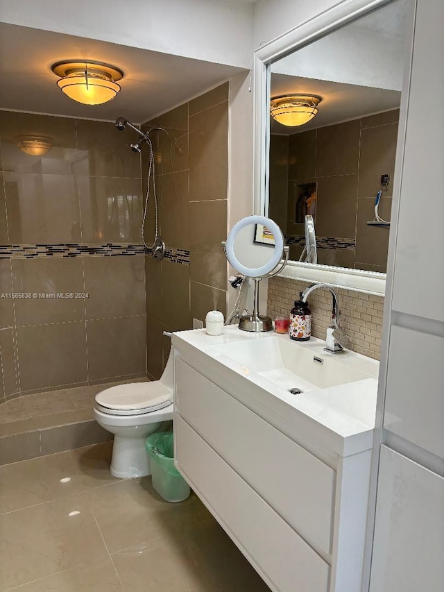 bathroom featuring a tile shower, tile patterned flooring, backsplash, toilet, and vanity