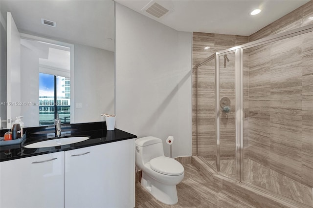 bathroom with a shower with door, vanity, wood-type flooring, and toilet