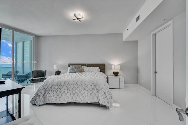 tiled bedroom featuring floor to ceiling windows, a water view, and access to exterior