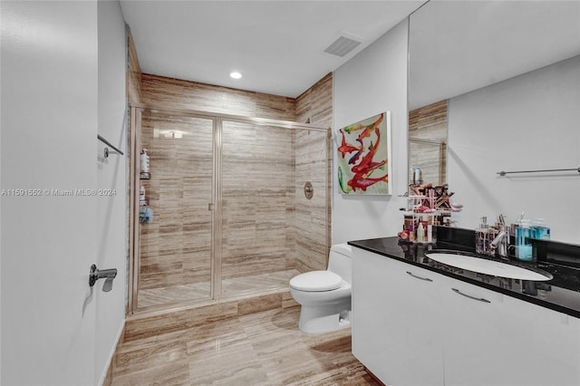 bathroom with an enclosed shower, vanity, and toilet