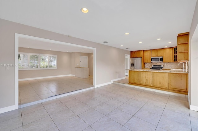 kitchen with sink, decorative backsplash, light tile patterned floors, kitchen peninsula, and stainless steel appliances