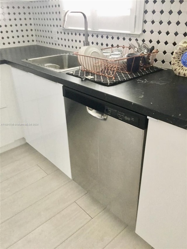 kitchen featuring white cabinets, sink, light tile flooring, and stainless steel dishwasher