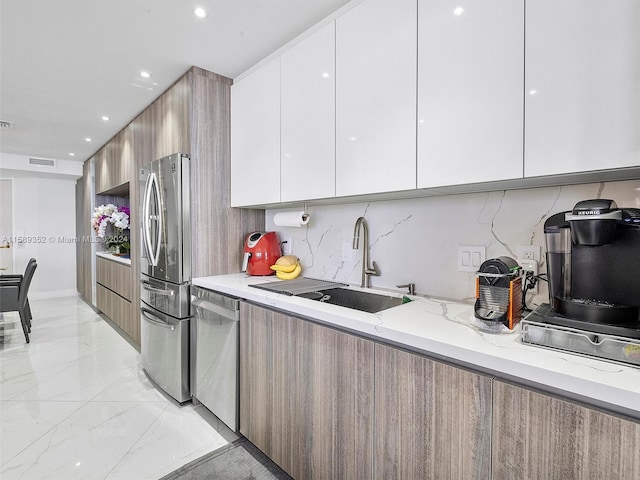 kitchen featuring white cabinets, light stone counters, backsplash, and appliances with stainless steel finishes