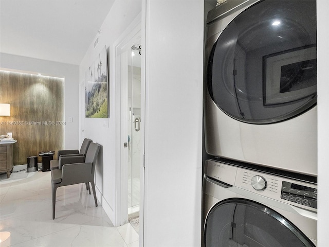 laundry room featuring stacked washing maching and dryer and light tile flooring