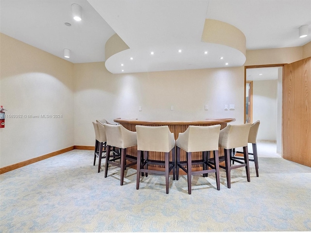 dining room featuring bar area and light carpet