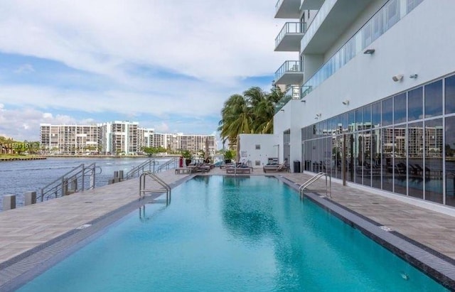 community pool featuring a water view, a view of city, and a patio