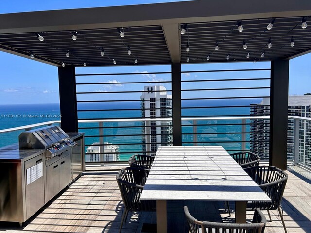 view of patio / terrace featuring area for grilling, an outdoor kitchen, a balcony, and a water view