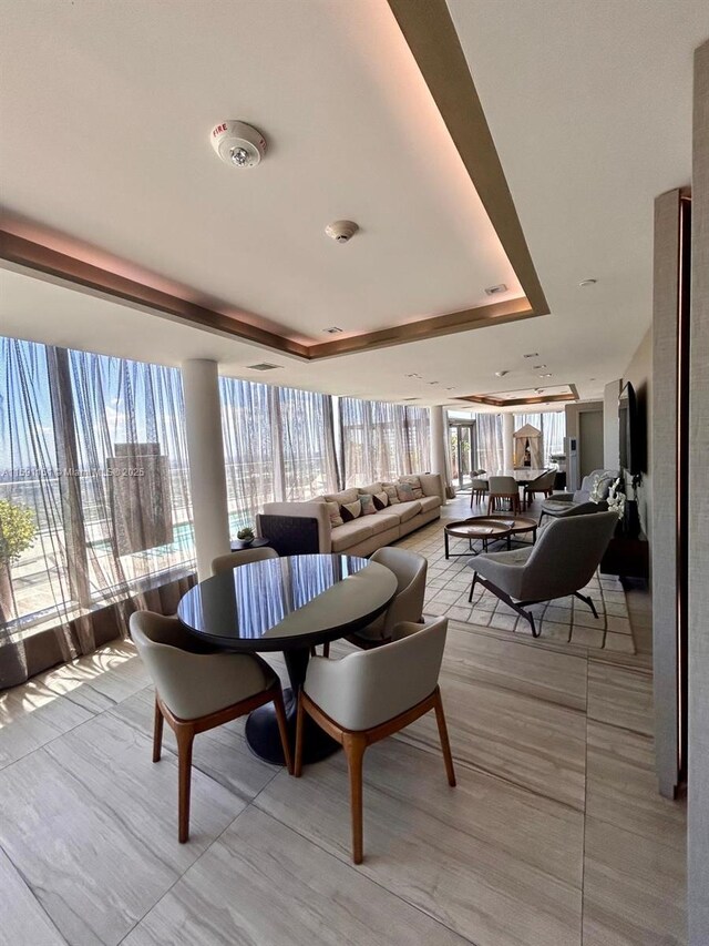 tiled dining space with a wealth of natural light and a tray ceiling