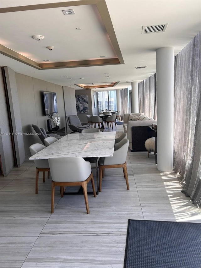 dining area with a tray ceiling and visible vents