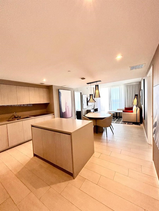 kitchen featuring modern cabinets, visible vents, light countertops, and a center island