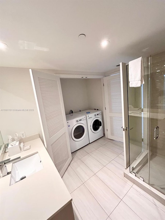 laundry room featuring light tile patterned floors, laundry area, washer and clothes dryer, and a sink