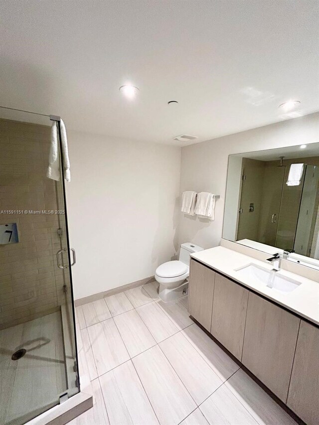 bathroom with vanity, toilet, tile floors, and a shower with door