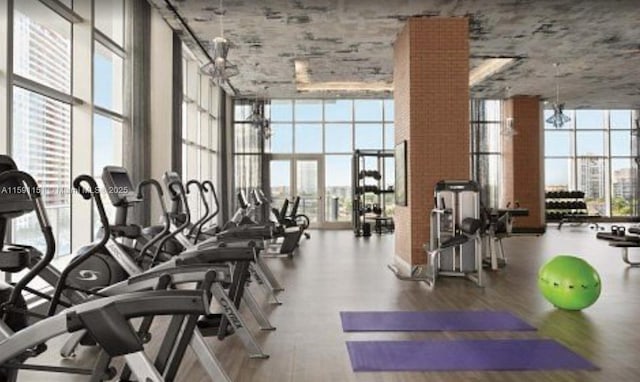 gym featuring a wall of windows, a city view, plenty of natural light, and wood finished floors