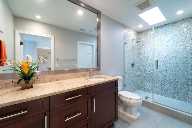 bathroom featuring a skylight, an enclosed shower, vanity, tile patterned flooring, and toilet