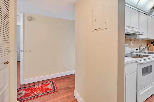 kitchen featuring light hardwood / wood-style floors, white range with electric cooktop, premium range hood, white cabinets, and a textured ceiling