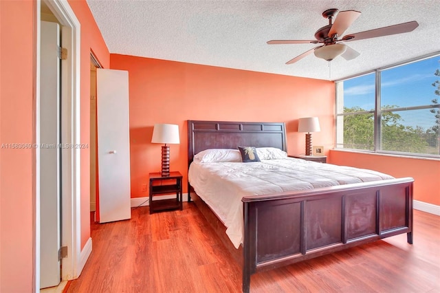 bedroom with baseboards, a ceiling fan, wood finished floors, and a textured ceiling
