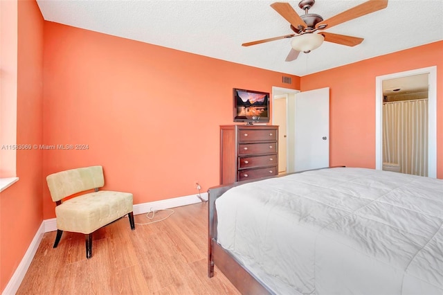 bedroom with a textured ceiling, ceiling fan, and hardwood / wood-style floors