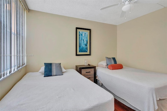 bedroom with ceiling fan, a textured ceiling, and dark wood-type flooring