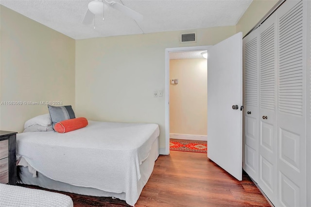 bedroom featuring wood-type flooring, a closet, ceiling fan, and a textured ceiling