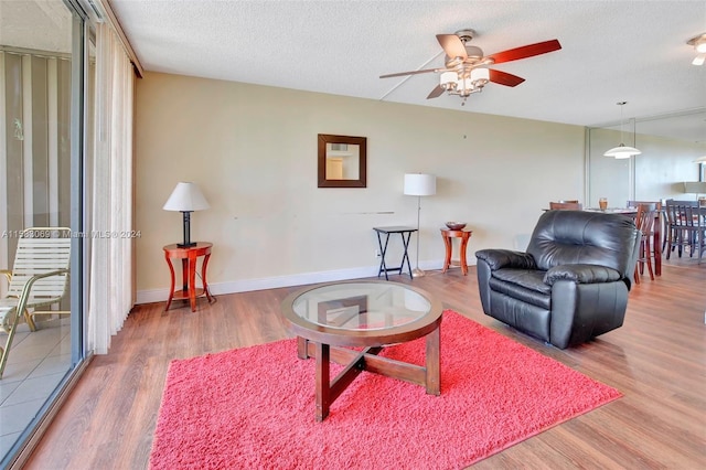 living room featuring ceiling fan, hardwood / wood-style flooring, and a textured ceiling