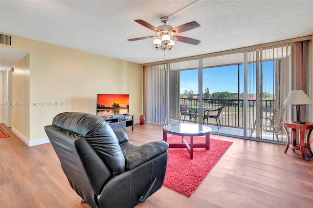 living room with a textured ceiling, ceiling fan, and hardwood / wood-style floors