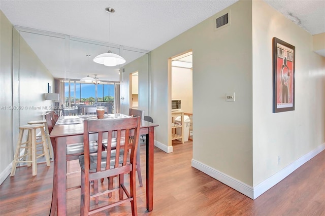 dining space with a textured ceiling, ceiling fan, and hardwood / wood-style floors