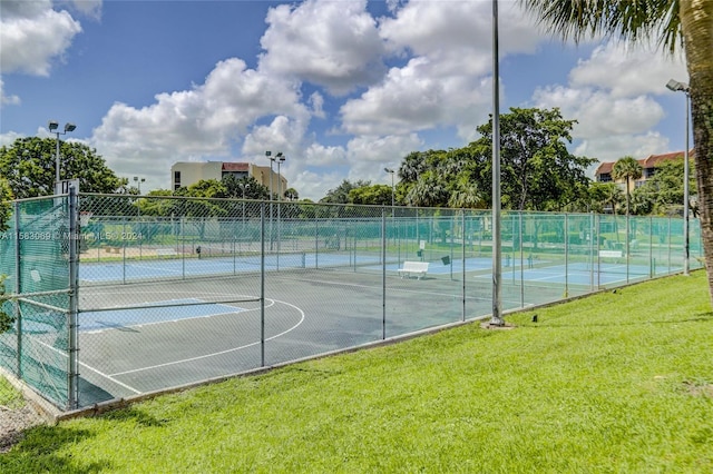 view of sport court with basketball hoop and a lawn