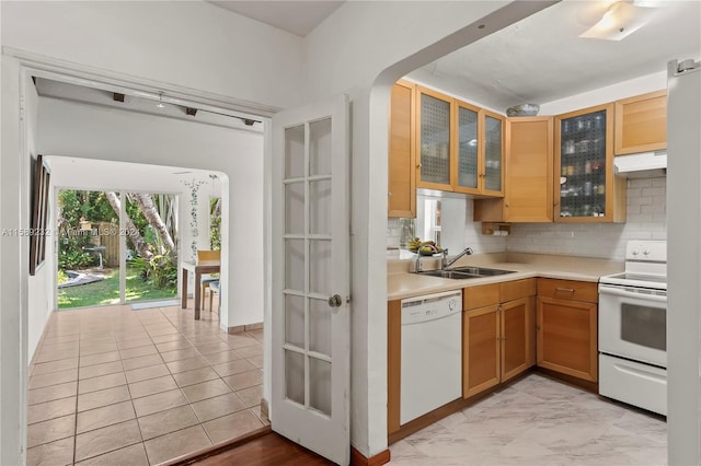 kitchen featuring tasteful backsplash, white appliances, light tile flooring, premium range hood, and sink