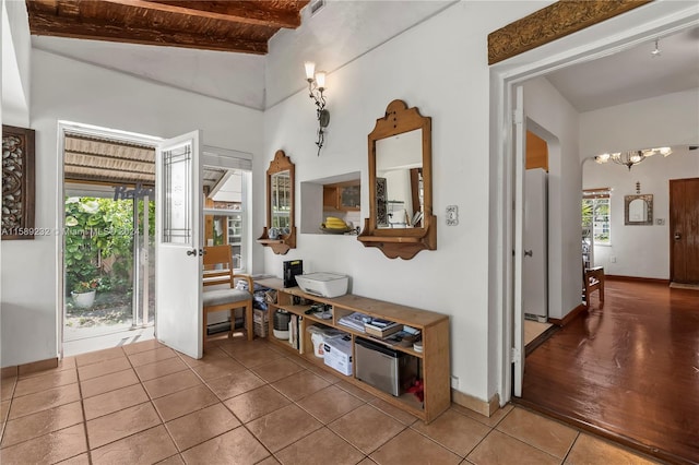 interior space with a notable chandelier, lofted ceiling with beams, and hardwood / wood-style flooring