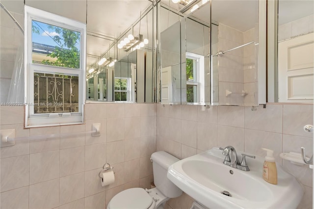 bathroom featuring sink, tile walls, and toilet