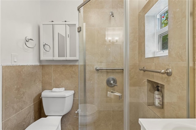 bathroom featuring a shower with shower door, tile walls, and toilet