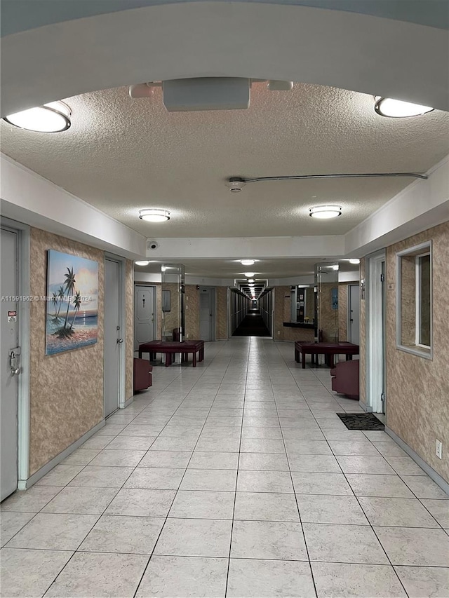 interior space with a textured ceiling and light tile flooring