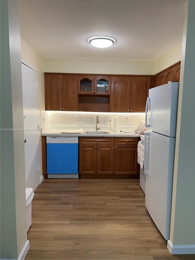 kitchen with white refrigerator, hardwood / wood-style flooring, tasteful backsplash, dishwashing machine, and sink