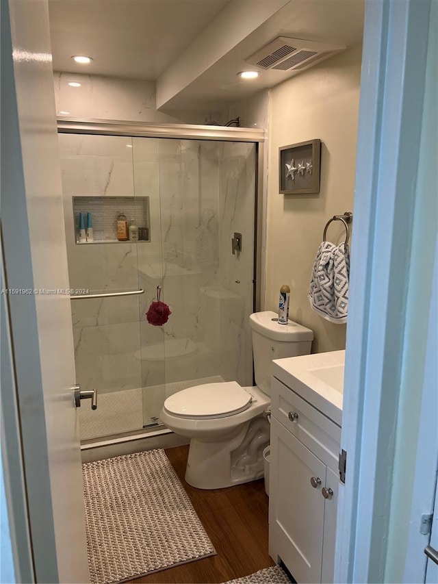 bathroom featuring an enclosed shower, vanity, toilet, and hardwood / wood-style floors