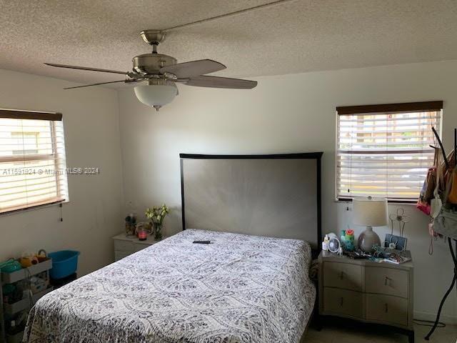 bedroom with ceiling fan and a textured ceiling