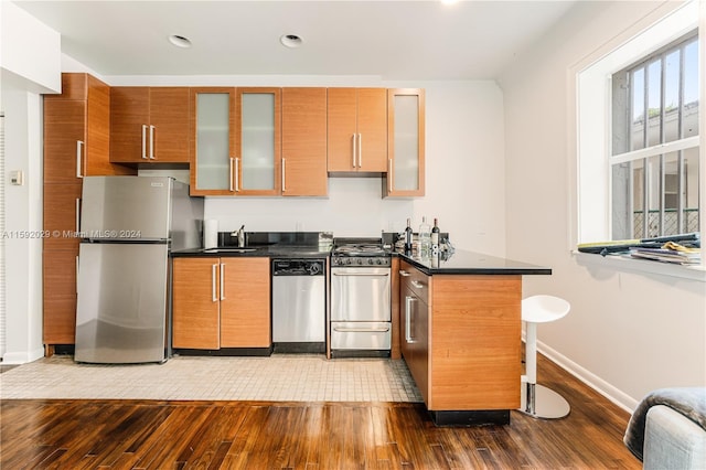 kitchen featuring tile floors, stainless steel appliances, kitchen peninsula, and sink