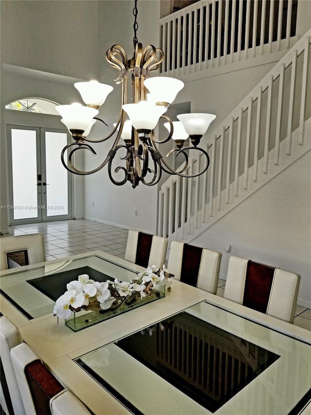 tiled dining space with a high ceiling, french doors, and an inviting chandelier