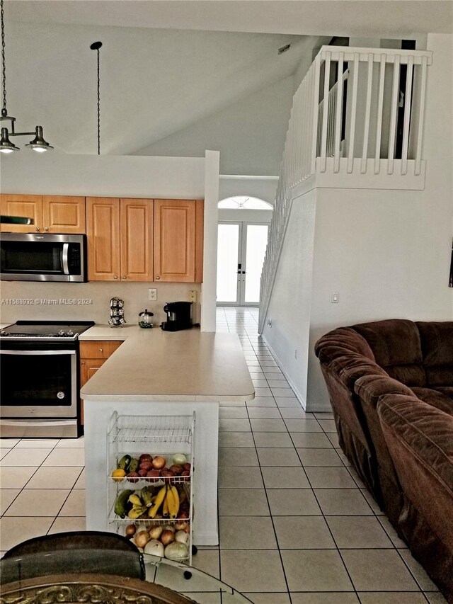 kitchen featuring light tile patterned flooring, high vaulted ceiling, light brown cabinets, appliances with stainless steel finishes, and kitchen peninsula