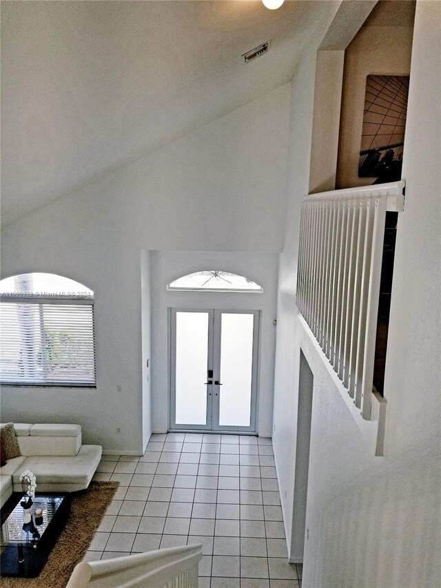 tiled foyer entrance featuring french doors and high vaulted ceiling