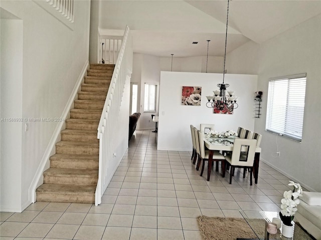 dining room with a notable chandelier, light tile patterned floors, and high vaulted ceiling