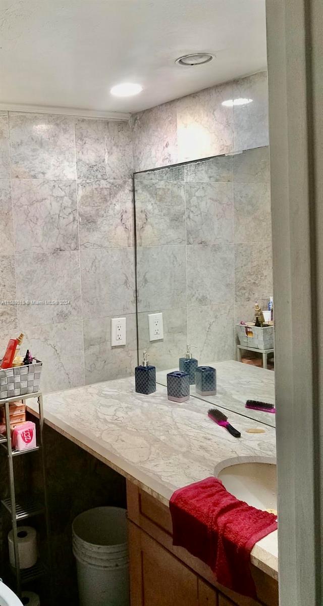 bathroom featuring vanity and tile walls