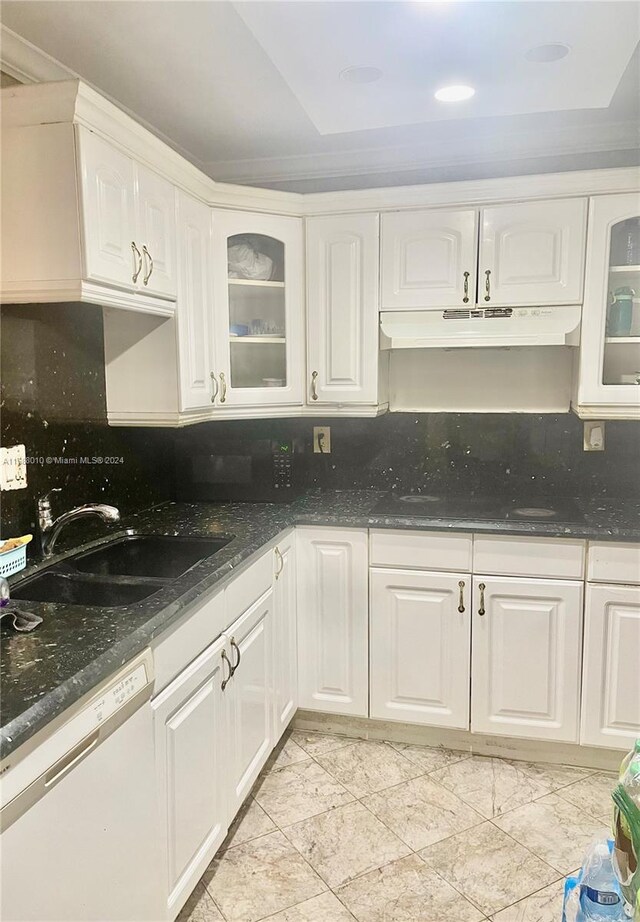 kitchen with dishwasher, dark stone countertops, backsplash, sink, and white cabinetry