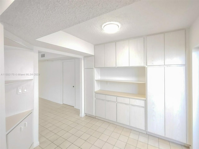 interior space featuring a textured ceiling and white cabinets