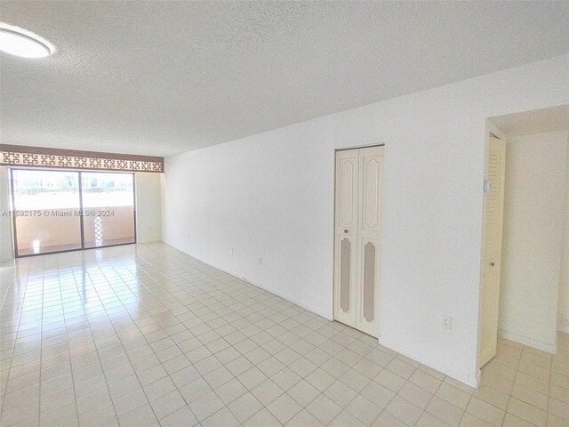 tiled empty room with a textured ceiling