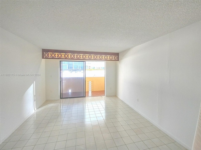 spare room with light tile patterned flooring and a textured ceiling