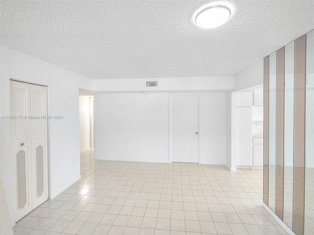 tiled empty room featuring a textured ceiling